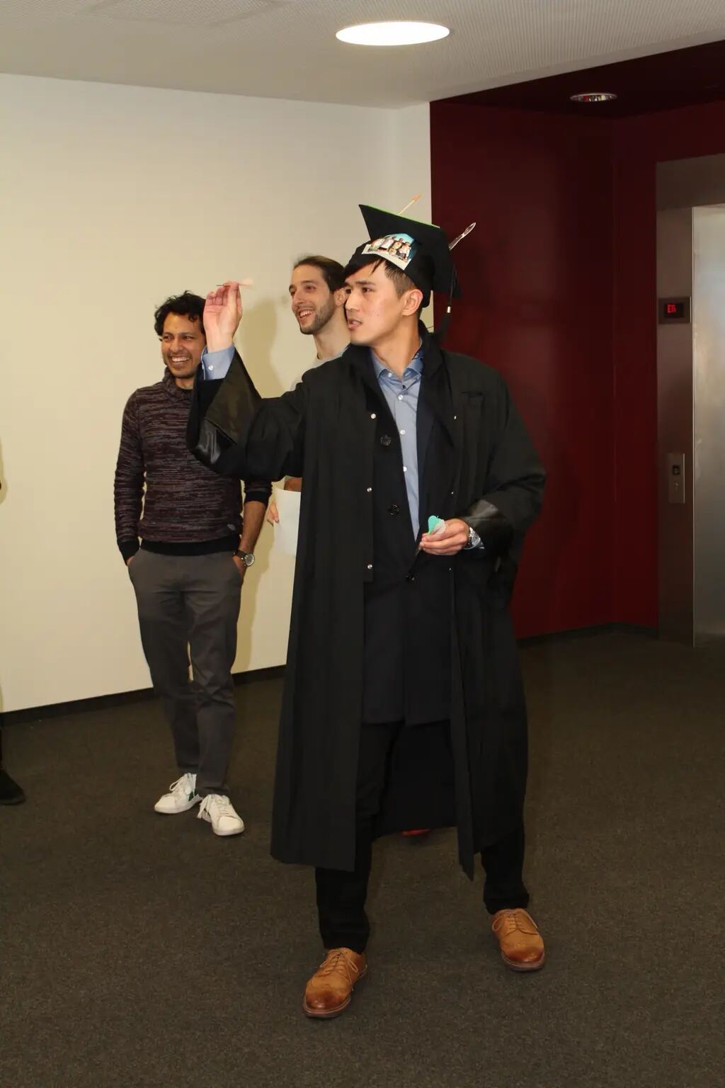 Wearing his doctoral hat, Ming-Yang Cheng takes part in a darts activity with colleagues after the defence
